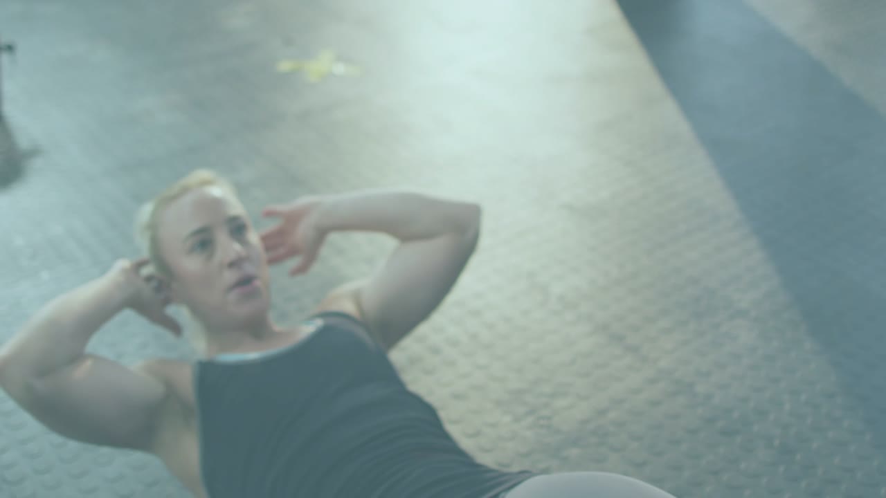 Woman tucking chin and doing crunches on gym floor, haze highlighting core for fitness, reclining