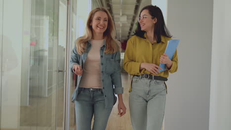 International-Women's-Day.-Business-females-walking-towards-the-camera-in-a-corridor.-People-go-to-a-work-meeting.