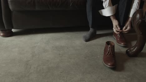 hands of young groom tying shoelaces on stylish brown shoes