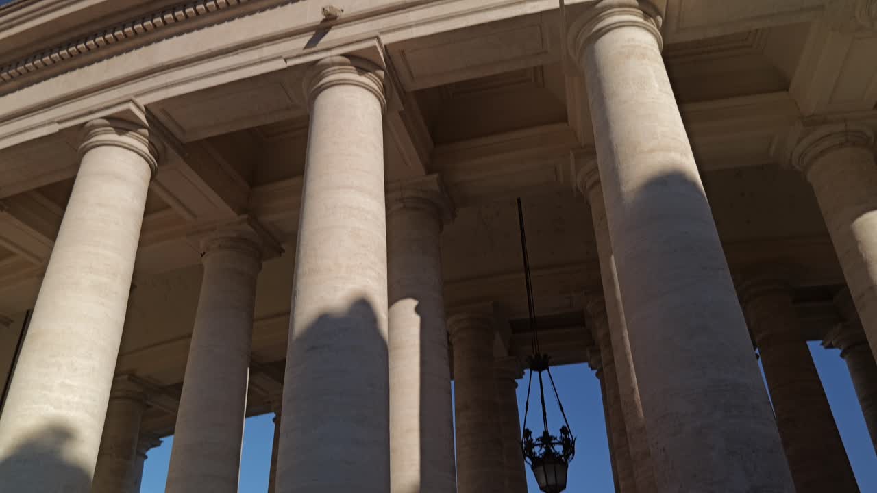 4K upward angle shot of the grand stone colonnade in St. Peter’s Square, Vatican City, Rome, highlighting architectural detail and historic Baroque design under clear skies