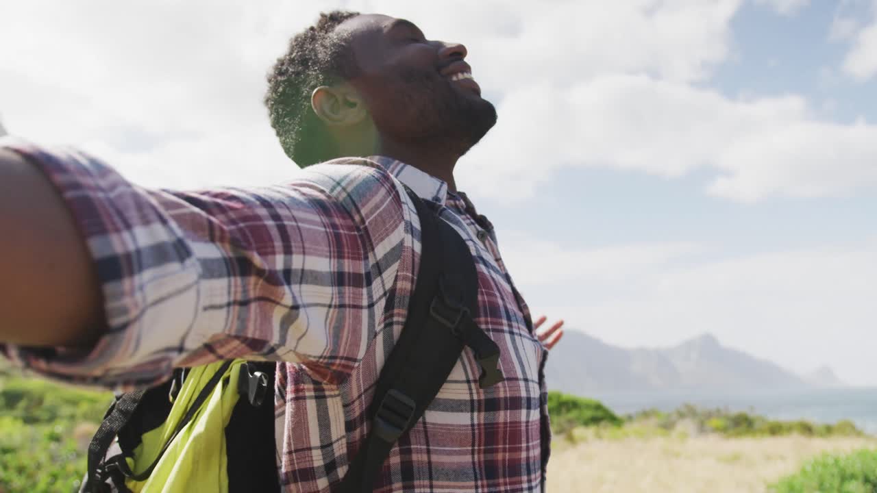 African american man standing with arms wide open while trekking in the mountains