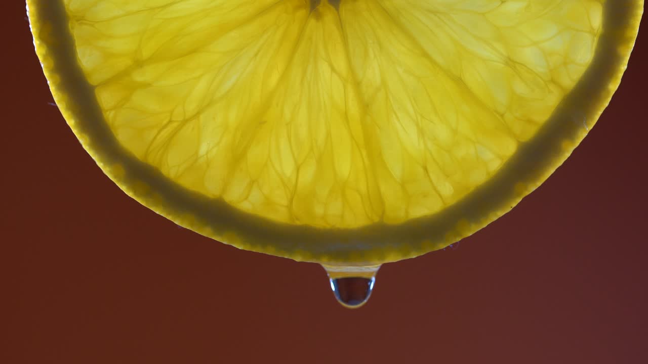 Fresh orange slice and water drop on red background, macro, closeup