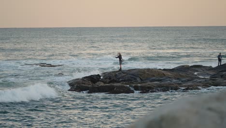 Hombre-Pescando-En-Agua-Salada-Desde-Rocas-Con-Olas-Rompiendo-Cerca