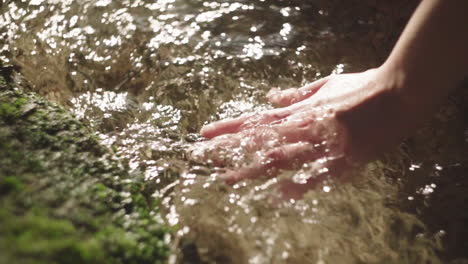 crop woman touching flowing water in river at night