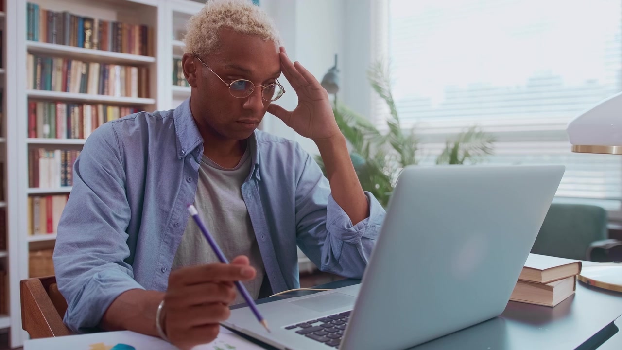 Sad african american businessman looking at laptop screen feeling stressed