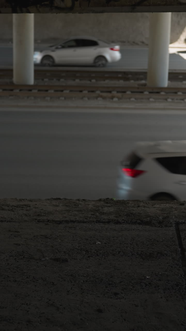 도시 도로에서 다리 아래로 운전하는 자동차의 가까운 시각, 그것은 지나가는 차량의 모션 흐릿함을 포착합니다