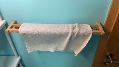 unique way of putting new fresh towel on wooden holder in bathroom with green blue wall