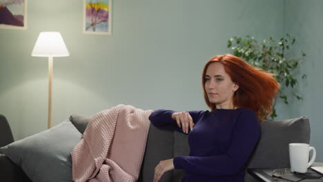 redhead woman comes to sit on sofa thinking about life