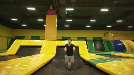 Slowmotion-footage-of-a-young-male-athlete-having-fun-jumping-on-professional-trampoline,-doing-somersaults.