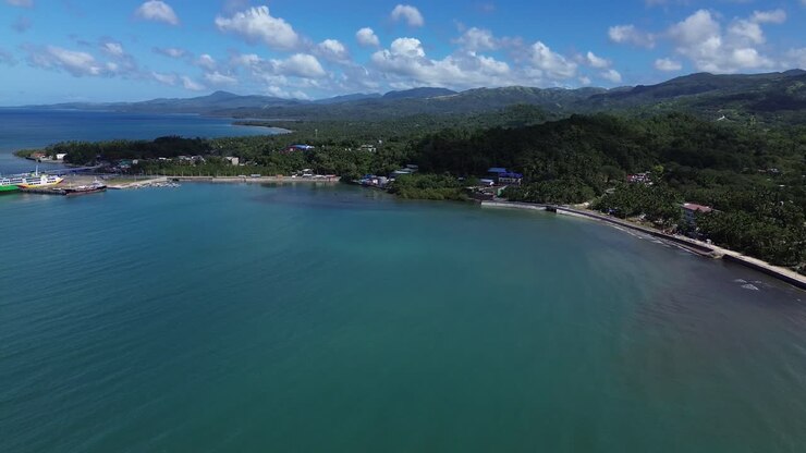 Vista aerea con drone del porto di Odiongan a Romblon, Filippine, che mostra un grande traghetto passeggeri attraccato al porto con la città costiera e la costa visibili sotto un cielo azzurro limpido in una giornata di sole