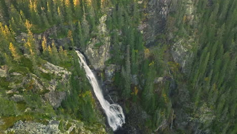 scenic waterfall in the heart of the swedish forest in autumn - aerial drone orbit