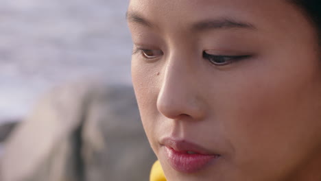 해가 지는 해변에서 자유를 탐험하는 심각한 독립적인 여성을 바라보는 해변에서 젊은 아시아 여성의 초상화