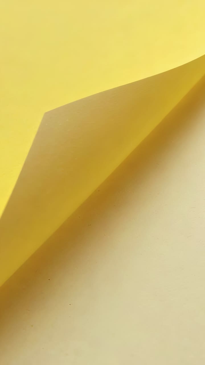Vertical video: Camera shifting, yellow sheet lifting corner to expose pale surface on cream mat