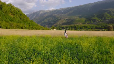 woman and child in white dresses stroll through spring flowering fields