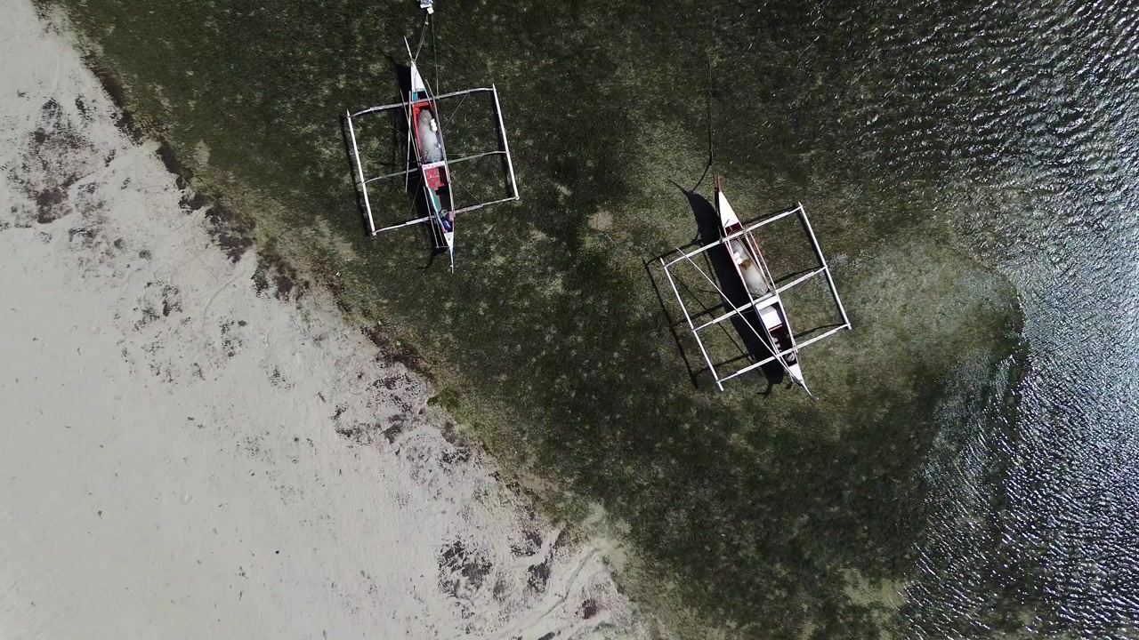 Top Down rise up Aerial view of traditional Bangka boats floating on calm tropical sea with clear water creating a peaceful minimal coastal scene around Bantayan Island Philippines Southeast Asia