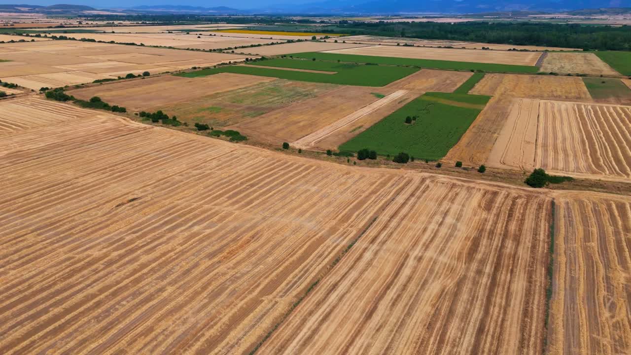 Dynamic high-speed drone footage racing over vast agricultural land, revealing corn, hay, sunflower, and cultivated fields stretching toward distant hazy hills