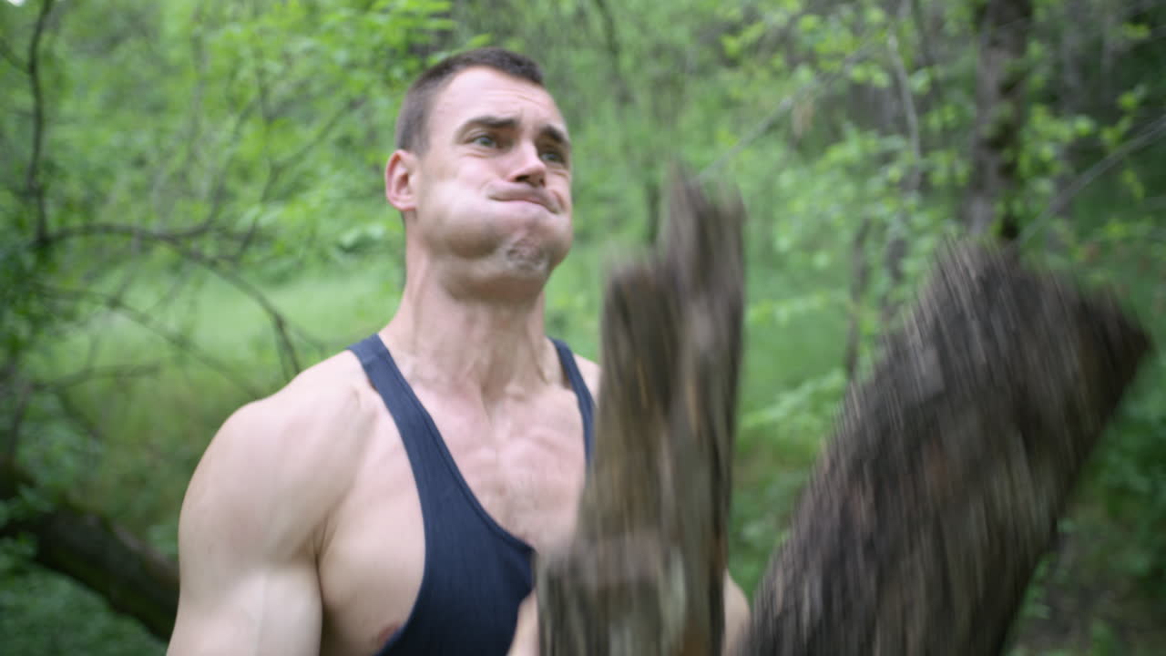Man exerting extreme effort while training with a log in the forest