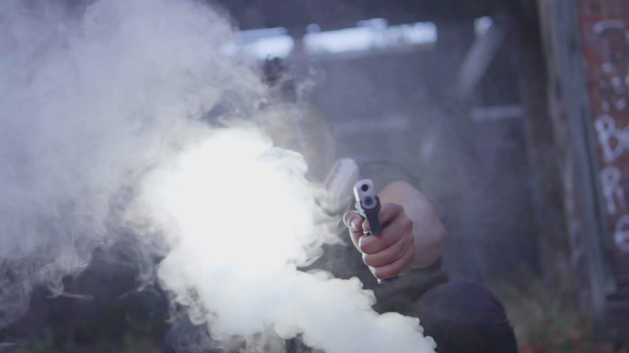 A masked figure emerges through thick smoke, aiming a pistol with flashlight in a dramatic, action-filled scene in an abandoned urban space