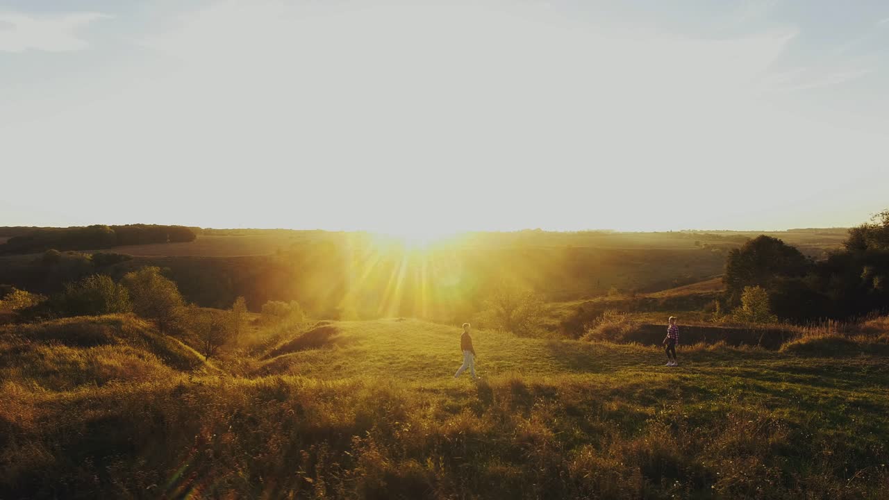 Loving Couple At Sunset. Aerial shot of a happy couple having fun outdoors. Couple walking on the meadow
