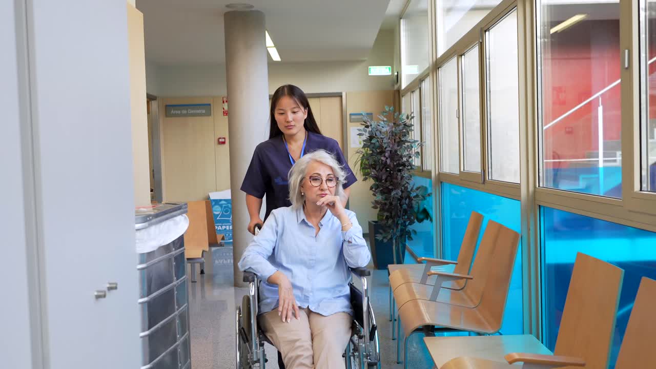 Infermiera che assiste un'anziana in sedia a rotelle in ospedale