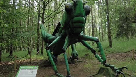 un saltamontes verde gigante exhibido en el bosque del parque kaszubski gigantow en polonia - ancho