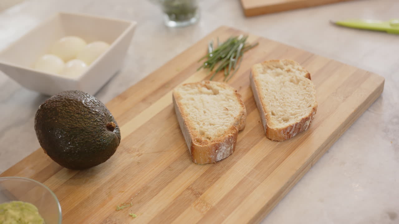 Preparing healthy meal, sliced bread on cutting board with avocado and chives