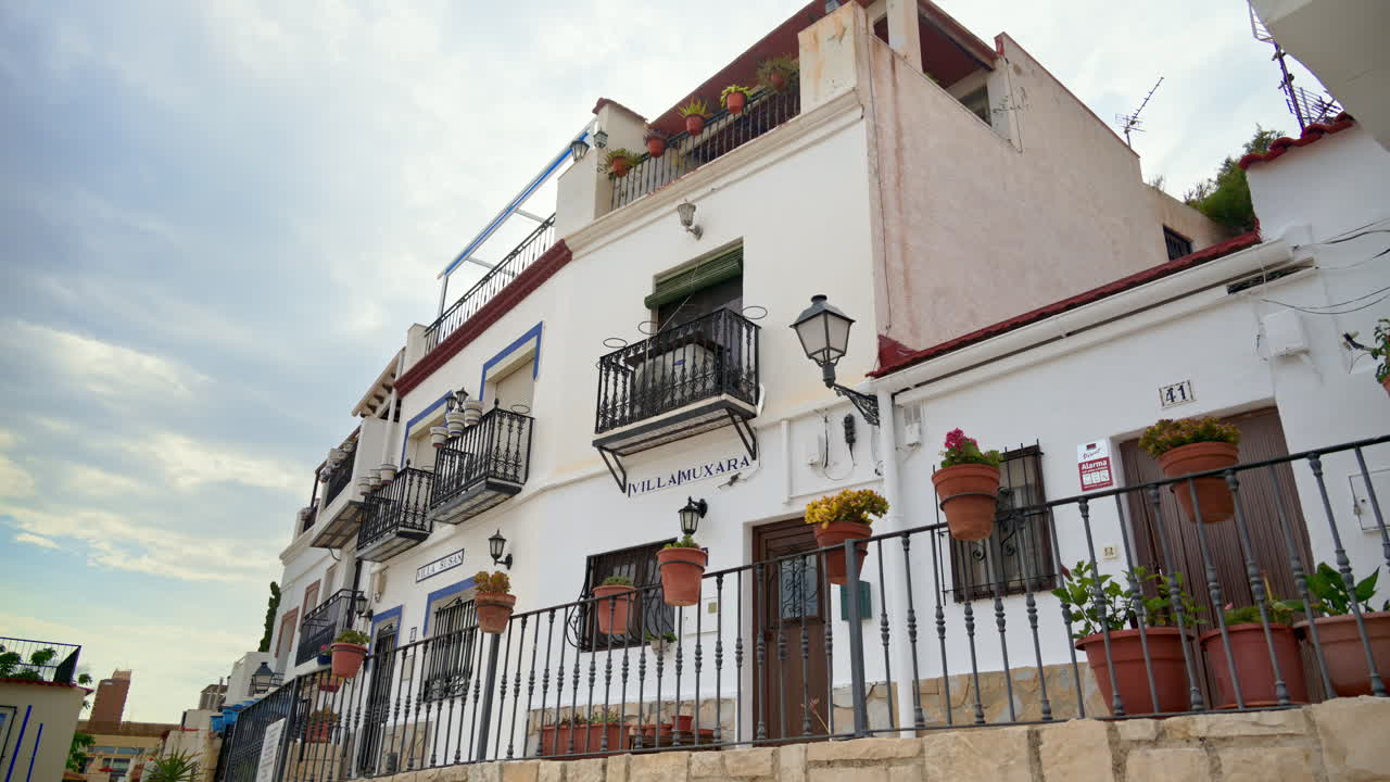 Alicante, Spain - May 20, 2025: Row of white houses with wrought iron balconies and terracotta pots in the old town