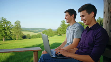 two young men using a laptop outdoors
