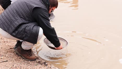 person panning for gold in muddy water