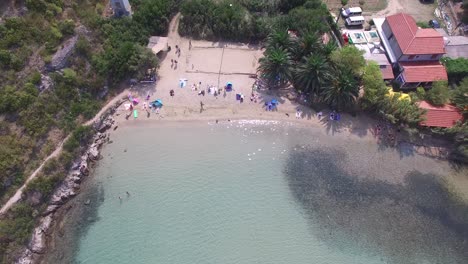 vista aérea de una cálida laguna clara y una playa llena de gente tomando el sol y nadando