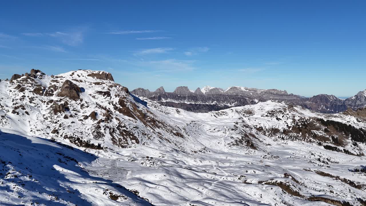 A sweeping aerial view of the Swiss Alps, showcasing the snowy slopes of Flumserberg and the iconic Churfirsten peaks. A majestic landscape of Flums in winter