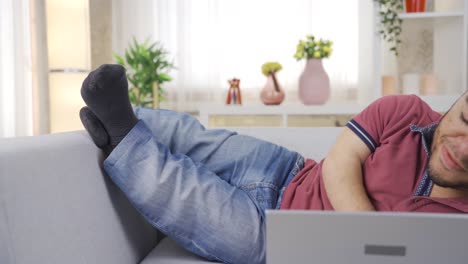 young man with dwarfism is using laptop at home and smiling happily, being happy.