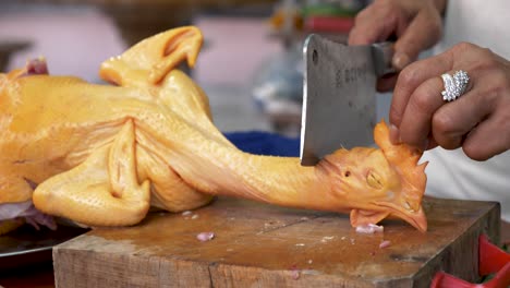 Thai-chef-prepares-to-chop-chicken-head-off,-motion-close-up-view