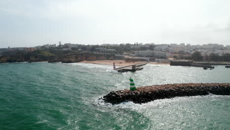 Majestic-aerial-view-of-waves-breaking-against-breakwater-structure-in-Lagos,-Portugal,-flying-forward,-day