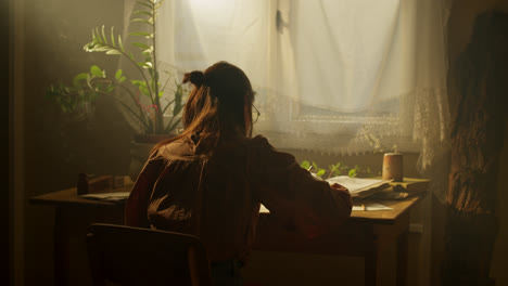woman writing at a vintage desk by the window