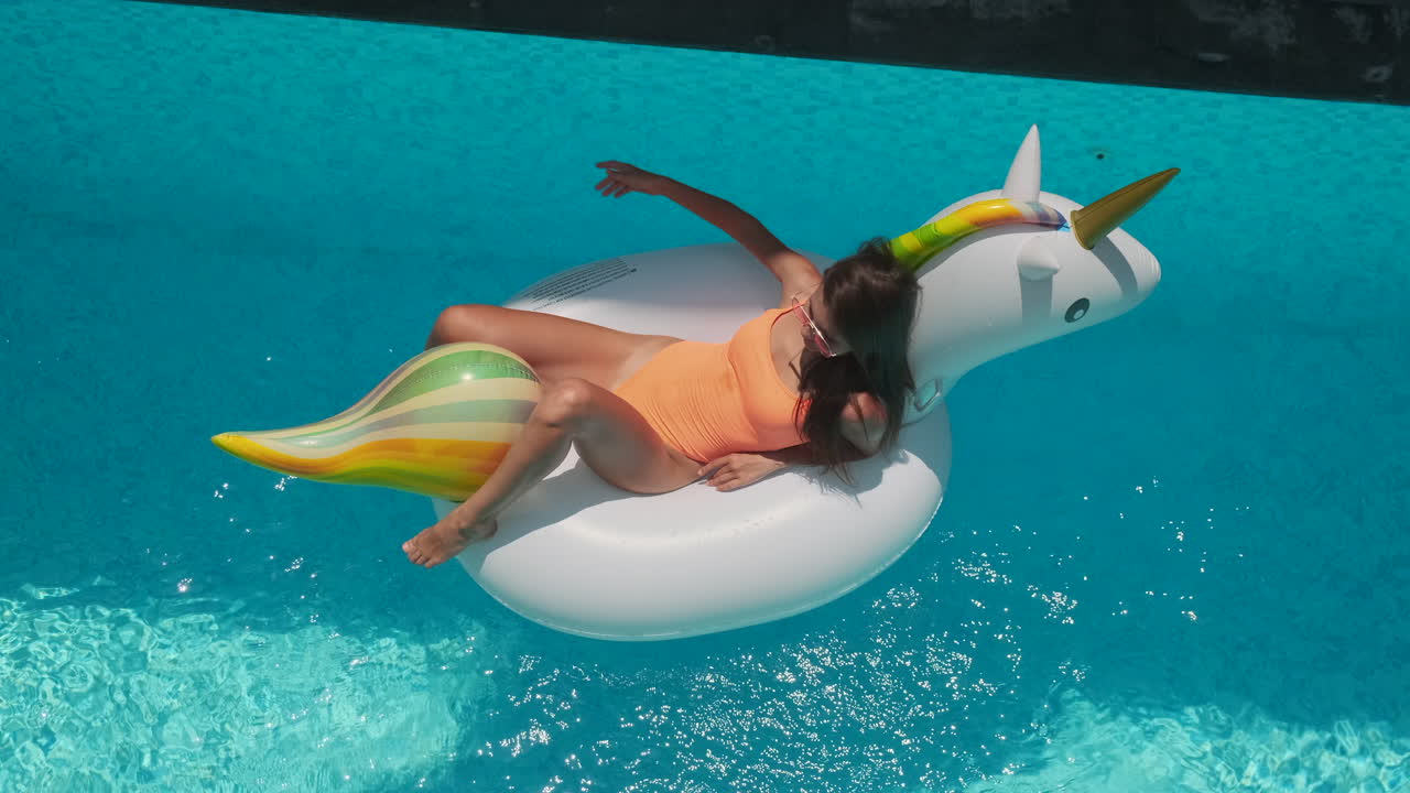 mujer relajándose en la piscina con flotador de unicornio