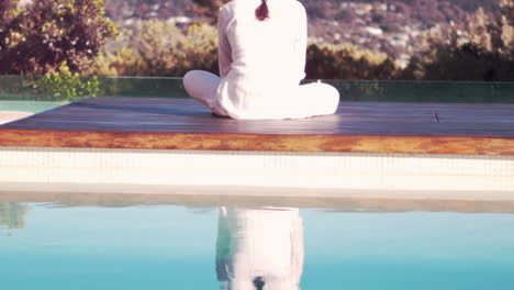 calm woman doing yoga by the pool