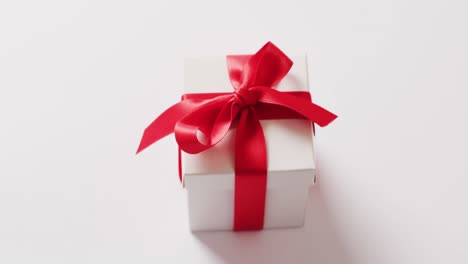 high angle video of white gift box tied with red ribbon, on white background with copy space