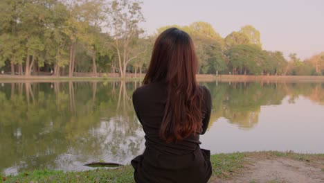 woman sitting by a lake in a park