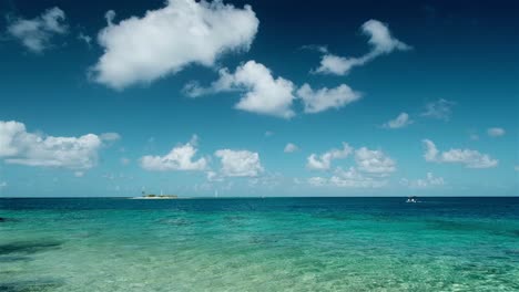 Blue-skies-and-turquoise-waters-with-a-small-island-and-boat-on-a-perfect-day-in-the-tropical-islands-of-Tuamoto-Atolls-in-the-South-Pacific