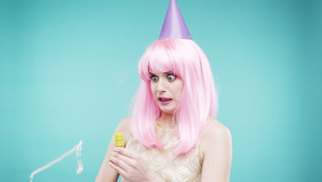 Crazy-face-pink-hair-woman-pulling-party-popper-slow-motion-photo-booth-blue-background