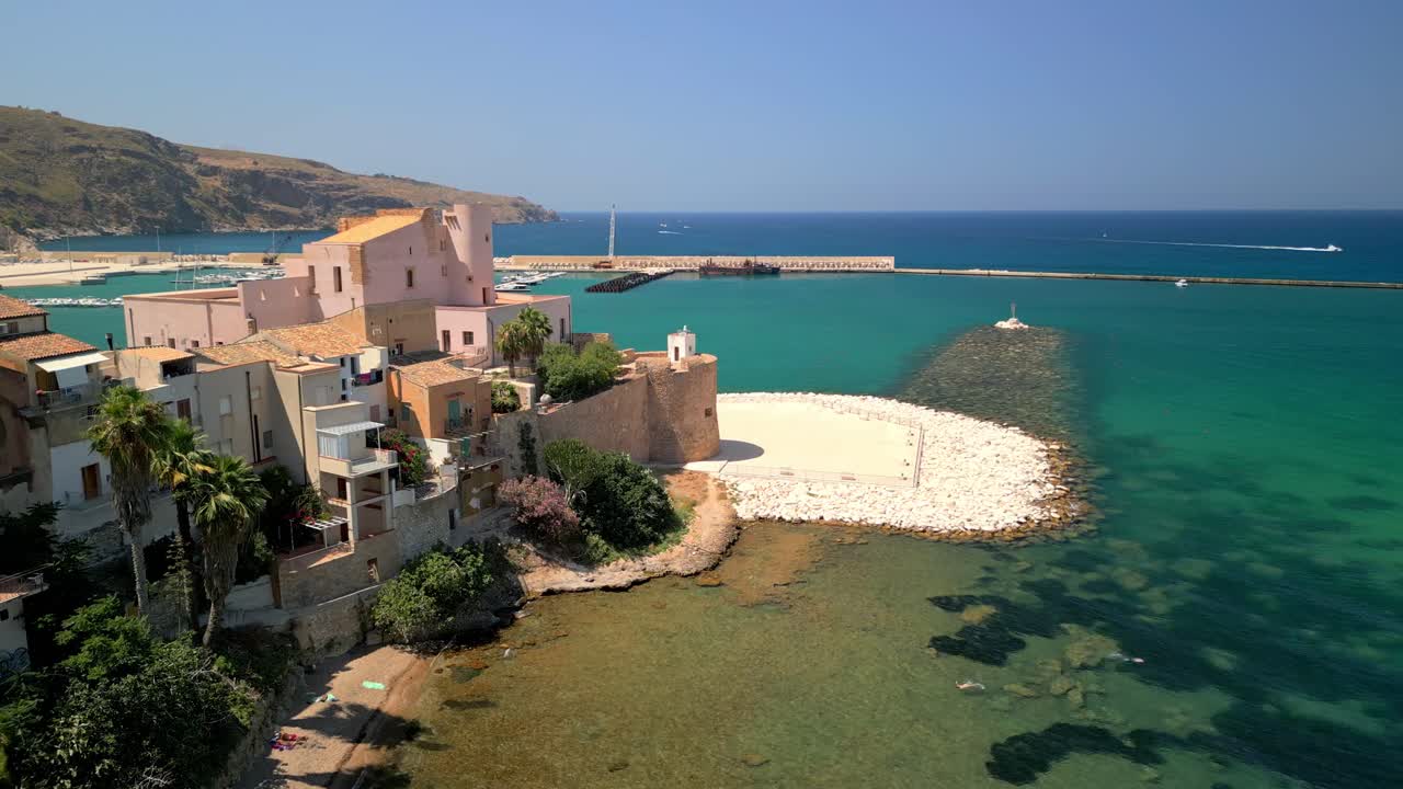 Luftpanorama over Terrasini med solbeskinnede bygninger og blide bølger. Droneoverflyvning der fremviser Terrasinis strand, havneinfrastruktur og kystarkitektur. Cinematisk droneoptagelse