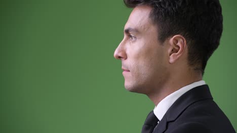young handsome hispanic businessman against green background