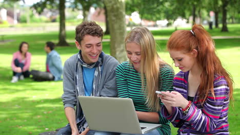 three students using laptop together and laughing