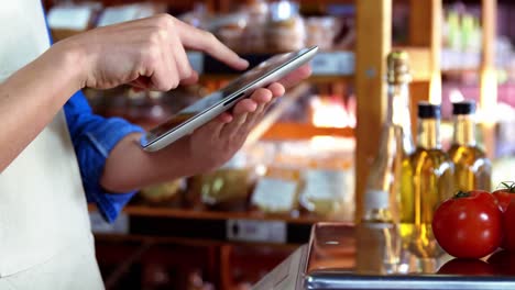 female staff using digital tablet in supermarket