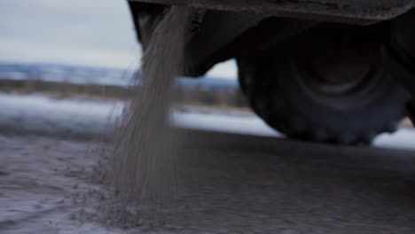 A-large-green-Claas-tractor-truck-with-trailer-salting-road-improving-grip-on-tarmac-with-gravel-on-frosty-winter-snowy-morning-in-northern-Norway-Scandinavia-on-top-hill-beautiful-view-forest-scenery