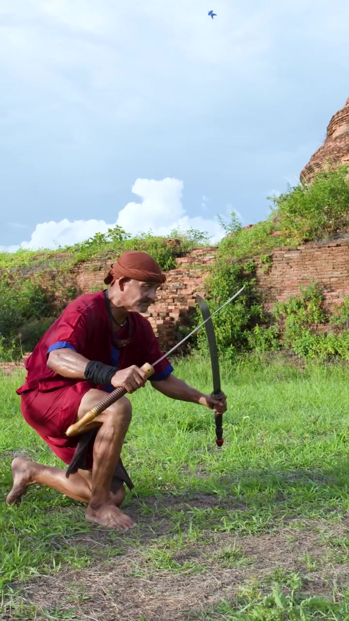 Artisti marziali thailandesi eseguono antichi rituali con la spada all'aperto davanti alle storiche rovine di un tempio in mattoni ad Ayutthaya