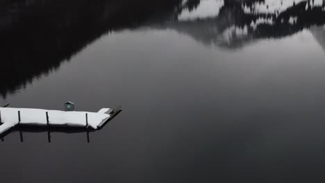 flying backwards very close to the water and over the ice past a raft on a mountain lake