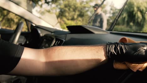 Close-up-of-a-male-wearing-black-gloves-cleaning-a-white-car-with-black-interior-with-a-microfiber-cloth-in-slow-motion