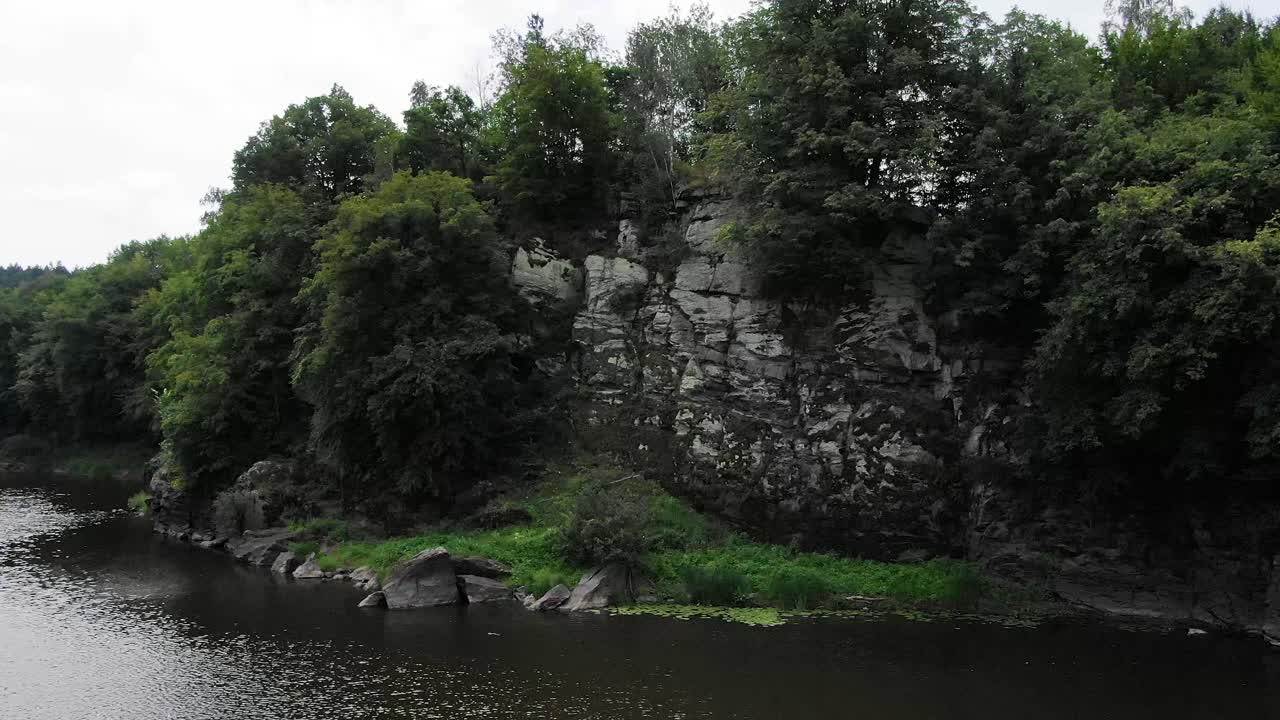 Veduta aerea di una ripida scogliera sul bordo di un fiume, circondata da fitta vegetazione forestale